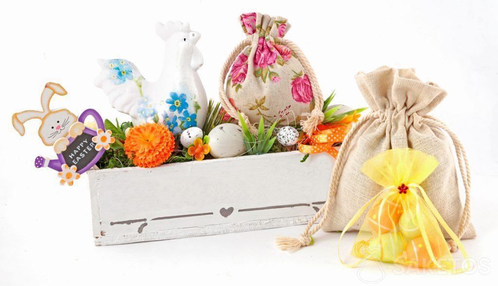 Barevné velikonoční kompozice z látkových sáčků a obdélníkového květináče s velikonoční vajíčkami.