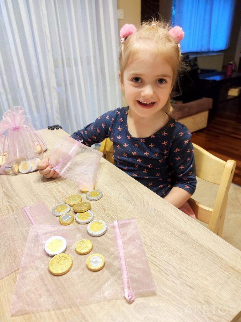 Dívka plní organzové sáčky čokoládovými mincemi