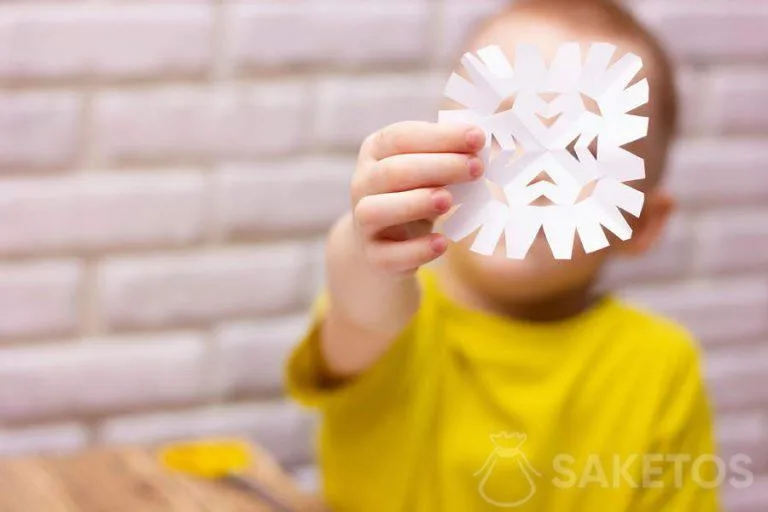 Dítě vystřihující sněhovou vločku z papíru